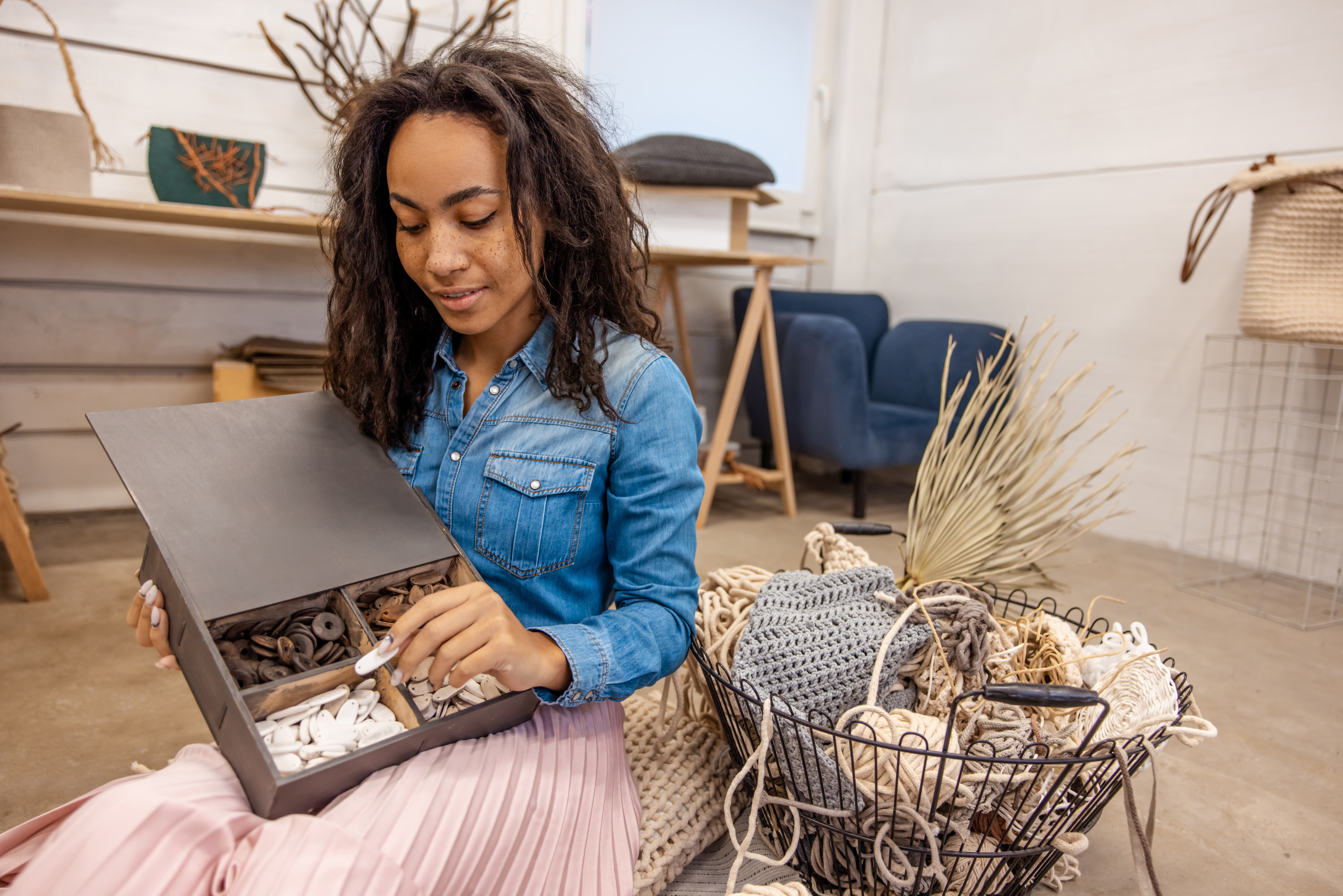 Buttons. Smiling dark-haired woman choosing buttons from the box